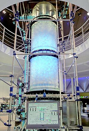 Großer metallischer Zylinder ragt über zwei Stockwerke und befindet sich in einem Labor.
