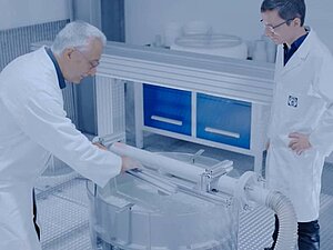 Zwei Wissenschaftler untersuchen ein weißes Rohr im Labor.