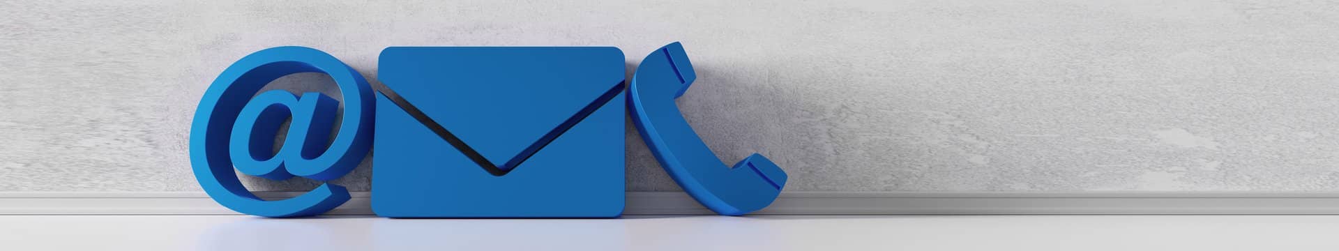 Ein blaues At-Zeichen, ein blauer Brief und ein blaues Telefon stehen an einer grauen Wand.
